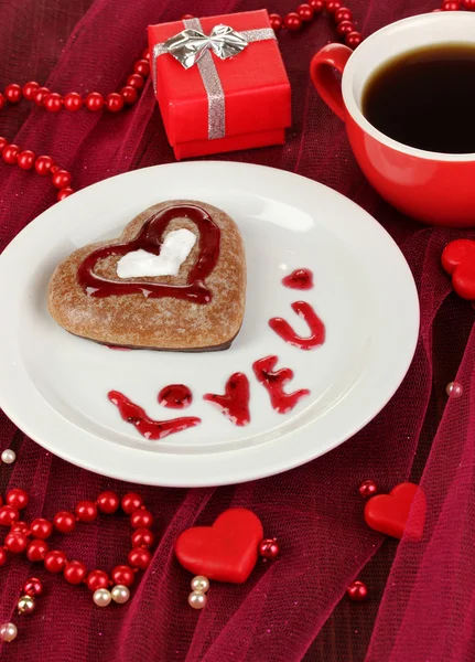 Biscotto al cioccolato a forma di cuore con tazza di caffè sulla tovaglia rosa primo piano — Foto Stock