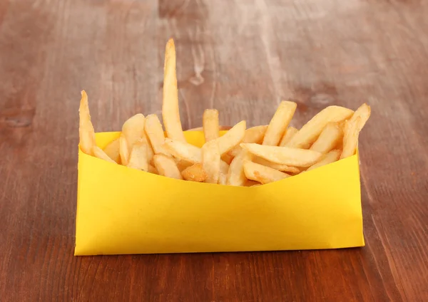 French fries in paper bag on wooden table close-up — Stock Photo, Image