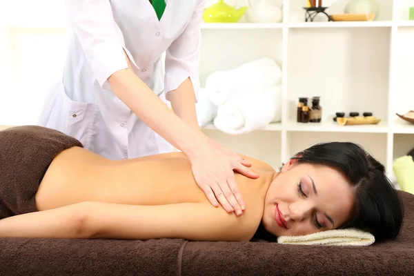Mulher bonita no salão de spa recebendo massagem, no fundo brilhante — Fotografia de Stock
