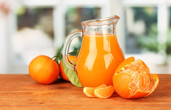 Voller Krug Mandarinensaft, auf Holztisch vor hellem Hintergrund — Stockfoto