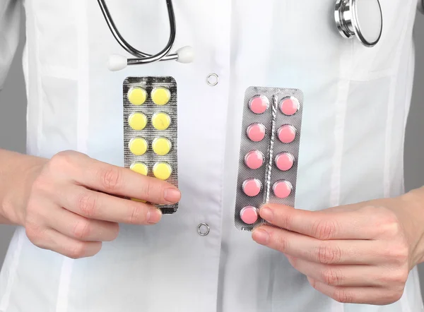 Close-up van vrouwelijke arts hand met pillen, op een achtergrond met kleur — Stockfoto