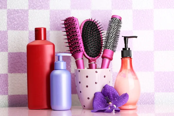Brosses à cheveux et bouteilles cosmétiques dans la salle de bain — Photo