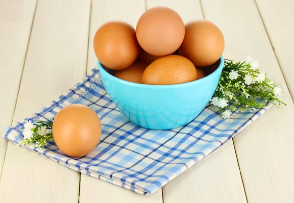 Яйца в синей миске на деревянном столе крупным планом — стоковое фото