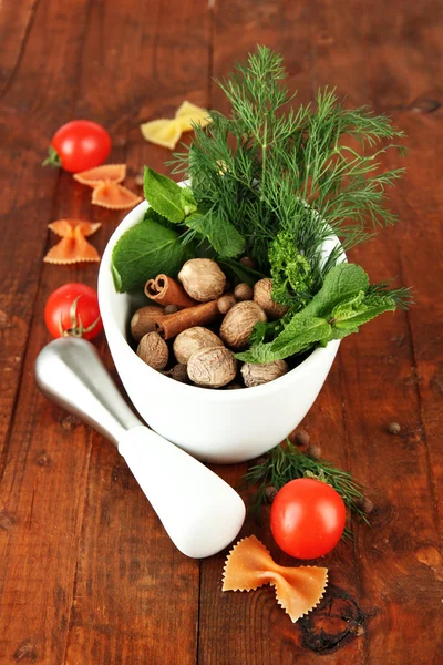 Herbs and spices in ceramic mortar, on wooden background — Stock Photo, Image