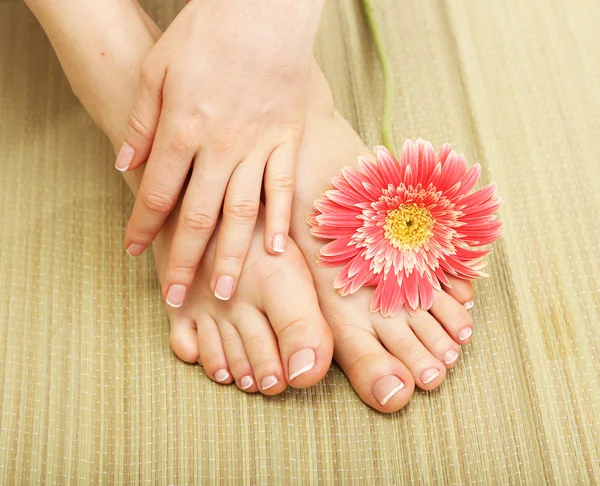 Beautiful woman legs and hand, on bamboo mat — Stock Photo, Image