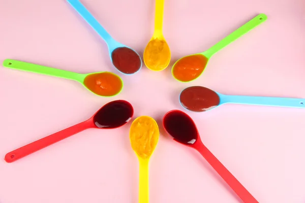 Puré de bebé en cucharas sobre fondo rosa — Foto de Stock