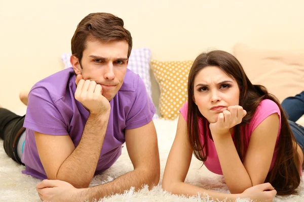 Young couple lying on carpet at home — Stock Photo, Image