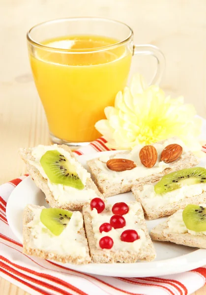 Sabrosos canapés con queso, kiwi y arándano, almendra, sobre plato de color, sobre fondo de madera — Foto de Stock