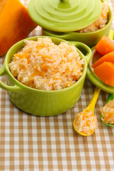 Taste rice porridge with pumpkin in saucepans on tablecloth background — Stock Photo, Image