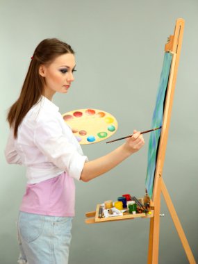 güzel bir genç kadın ressam gri arka plan üzerinde iş başında