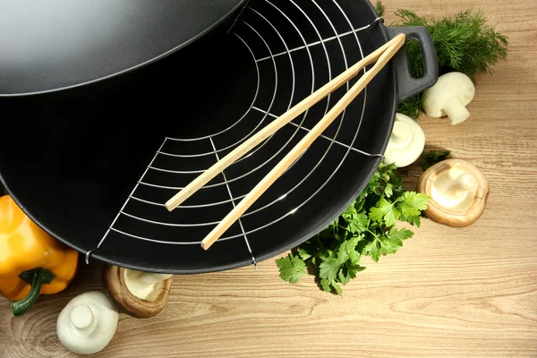 Sartén wok negro y verduras en la mesa de madera de la cocina, de cerca —  Fotos de Stock