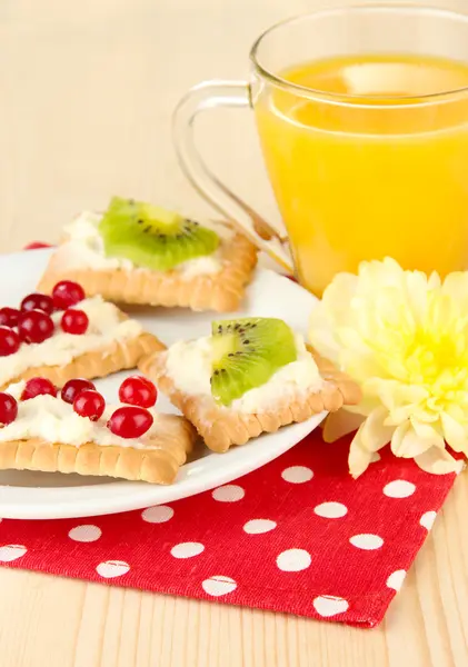 Tasty canapes with cheese and kiwi, cranberry, on color plate, on wooden background — Stock Photo, Image