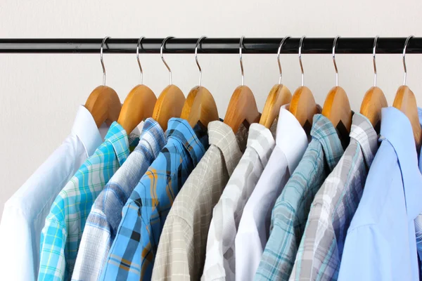 Shirts with ties on wooden hangers on light background — Stock Photo, Image