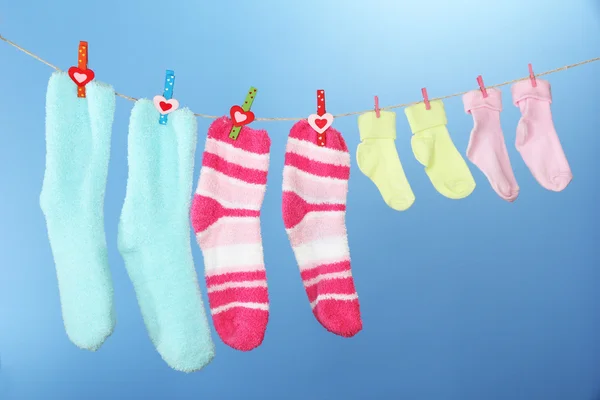 Colorful socks hanging on clothesline, on color background — Stock Photo, Image