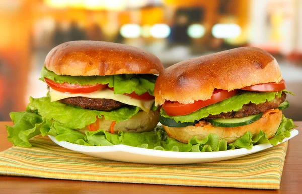 Big and tasty hamburgers on plate on table in cafe — Stock Photo, Image