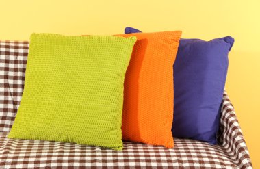 kanepede sarı arka plan üzerinde renkli yastıklar