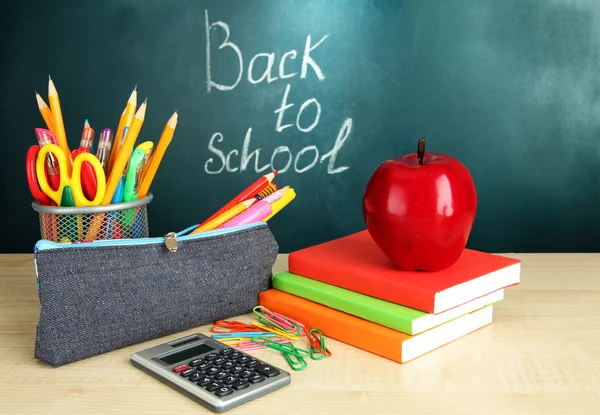 Voltar à escola - quadro-negro com caixa de lápis e equipamento escolar na mesa — Fotografia de Stock