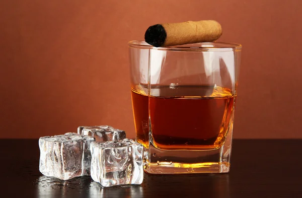 Glass of whiskey and cigar on brown background — Stock Photo, Image