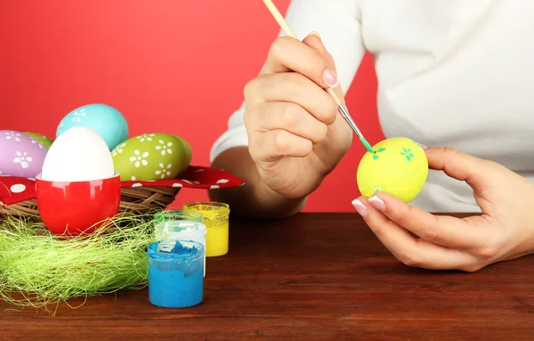 Giovane donna pittura uova di Pasqua, su sfondo di colore — Foto Stock