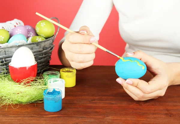 Young woman painting Easter eggs, on color background — Stock Photo, Image