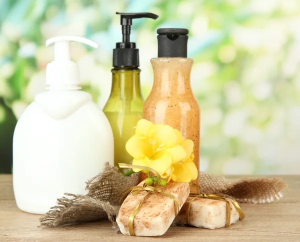 Vloeibare en handgemaakte zeep op houten tafel, op groene achtergrond — Stockfoto