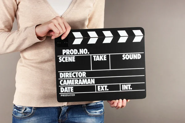 Movie production clapper board in hands on grey background — Stock Photo, Image