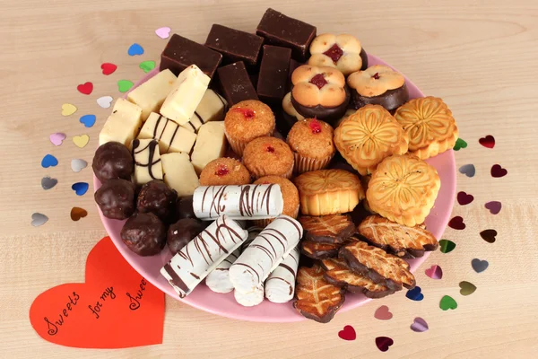 Sweet cookies with valentine card on plate on wooden background — Stock Photo, Image