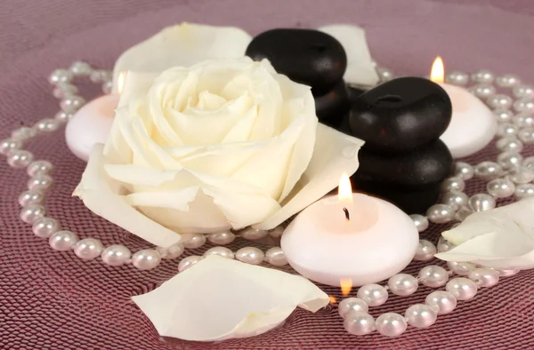 Piedras de spa con flores y velas en agua en el plato —  Fotos de Stock