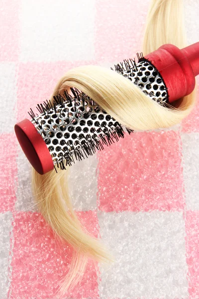 comb brush with hair on pink tile wall background