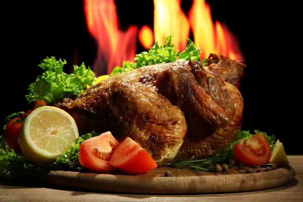 Pollo asado entero con verduras en plato, sobre fondo de llama —  Fotos de Stock