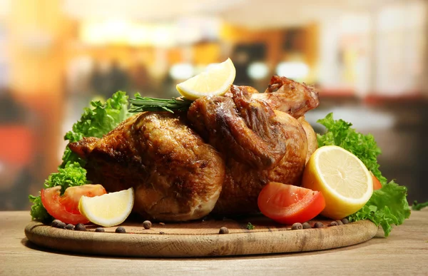 Poulet rôti entier avec légumes dans une assiette, sur une table en bois dans un café — Photo