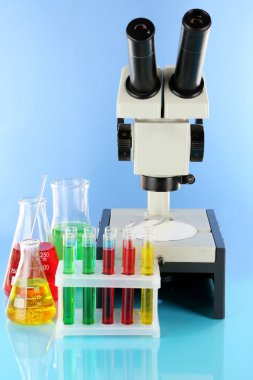 test tüpleri ile renkli sıvılar ve mikroskop mavi zemin üzerine
