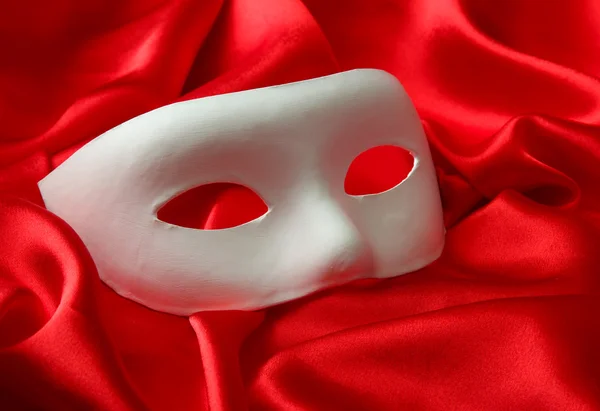 White mask, on red silk fabric — Stock Photo, Image