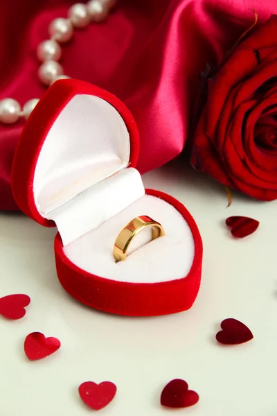 Krásné krabice s snubní prsten a rose na červené hedvábné pozadí — Stock fotografie