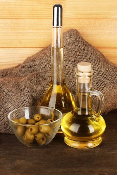 Different types of oil with olives on wooden background — Stock Photo, Image