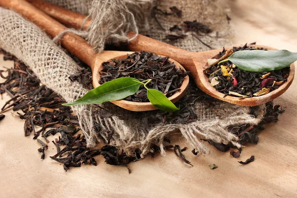 Dry tea with green leaves in wooden spoons, on wooden background — Stock Photo, Image