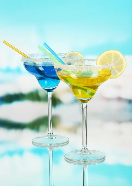 Gele en blauwe cocktails in glazen op blauwe natuurlijke achtergrond — Stockfoto