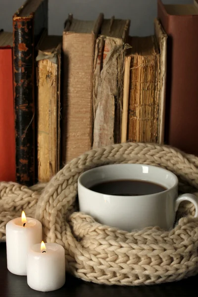 Kopp kaffe insvept i halsduk på böcker bakgrund — Stockfoto