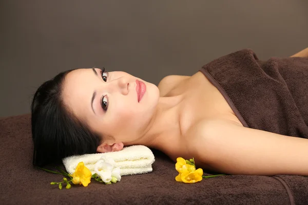 Beautiful young woman in spa salon, on dark background — Stock Photo, Image