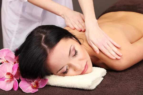 Beautiful young woman in spa salon getting massage with spa stones, on dark background — Stock Photo, Image