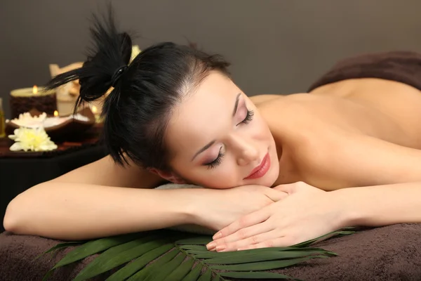 Beautiful young woman in spa salon, on dark background — Stock Photo, Image