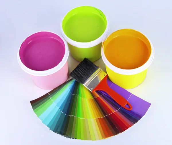 Paint pots, paintbrushes and coloured swatches close up — Stock Photo, Image