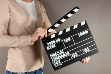 Film üretim clapper panosundaki gri arka plan üzerinde eller