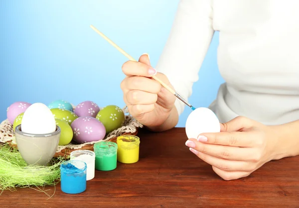 Mujer joven pintando huevos de Pascua, sobre fondo de color — Foto de Stock