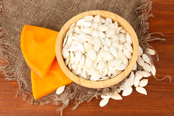 Pumpkin seeds in wooden bowl, on wooden background — Stock Photo, Image