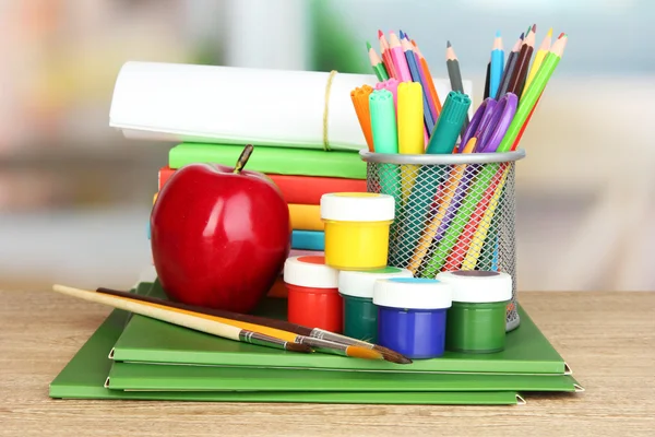 Школьные принадлежности с яблоком на деревянном столе — стоковое фото
