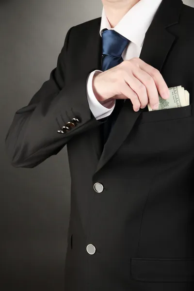 Iş adamı siyah arka plan üzerine cebinden para saklıyor — Stok fotoğraf