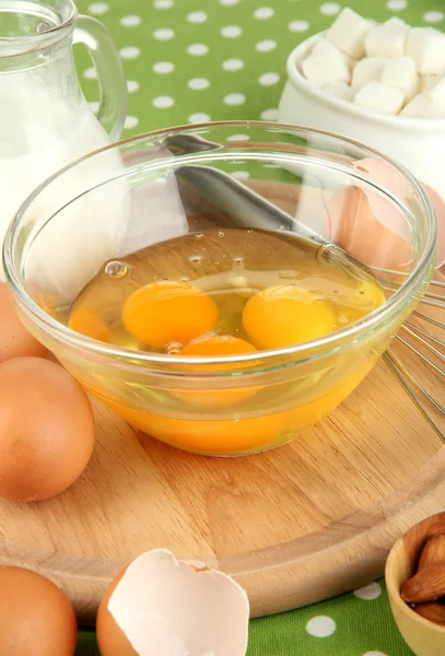 Zerbrochenes Ei in Schüssel und verschiedene Zutaten daneben auf grüner Tischdecke in Großaufnahme — Stockfoto