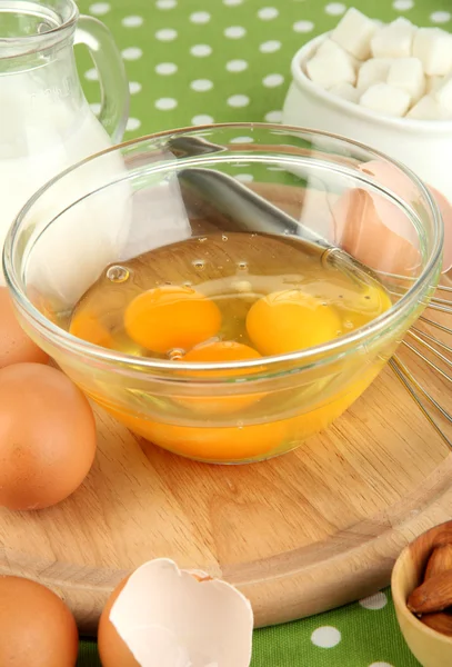 Ovo quebrado na tigela e vários ingredientes ao lado deles na toalha de mesa verde close-up — Fotografia de Stock