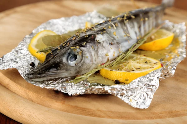 Folyo otlar ve ahşap masa yakın çekim üzerinde kurulu limon ile balık — Stok fotoğraf